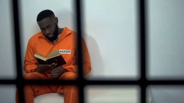 Inmate reading a book behind bars — a symbol of hope through learning
